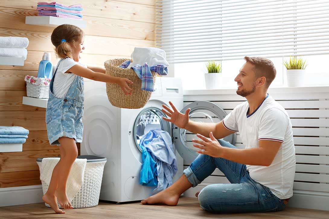 Daughter tossing a basket of laundry to father to place in dryer
