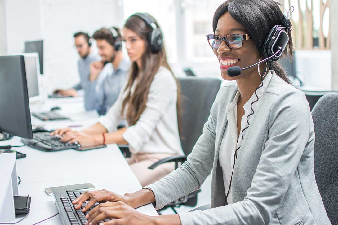 Four customer service agents wearing headsets and working on the computer