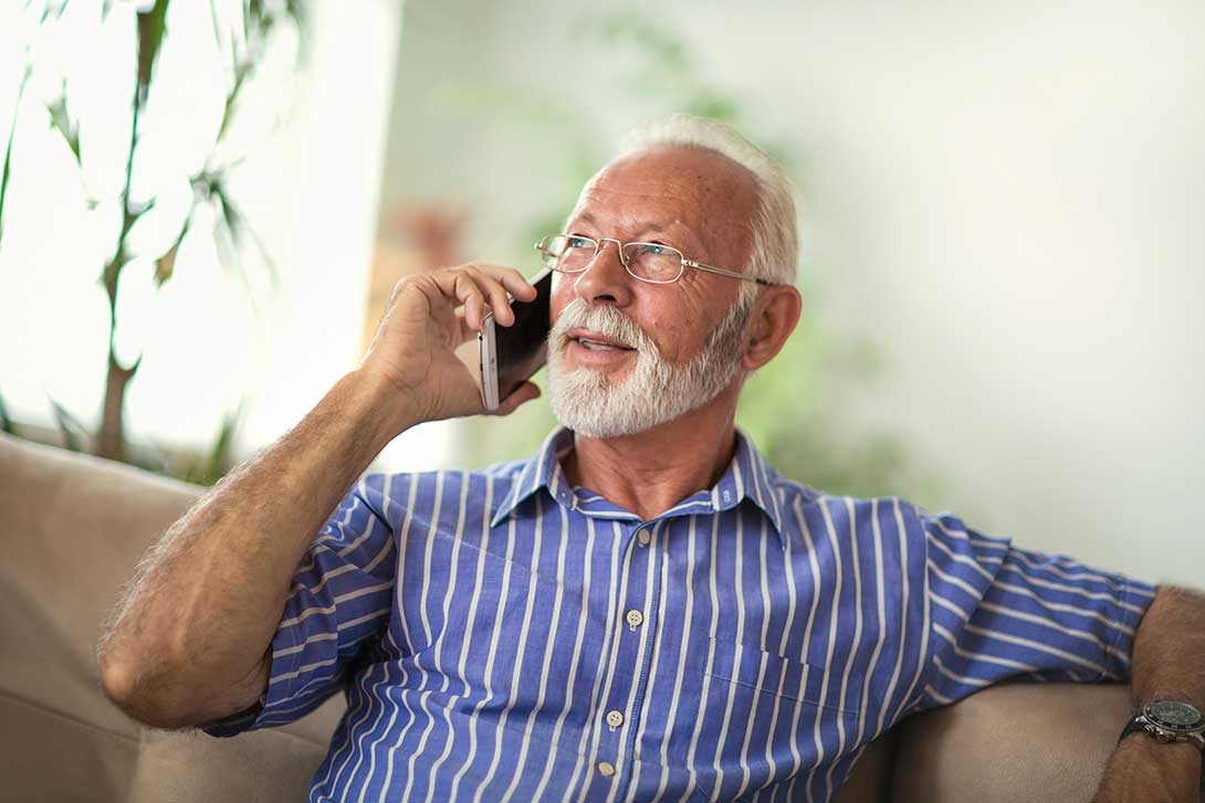 Elderly man sitting on the couch and talking on a mobile phone