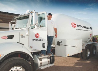 Smiling man wearing baseball hat standing in the door of a propane bobtail truck