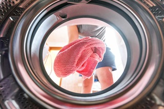 Woman throwing a pink towel into dryer