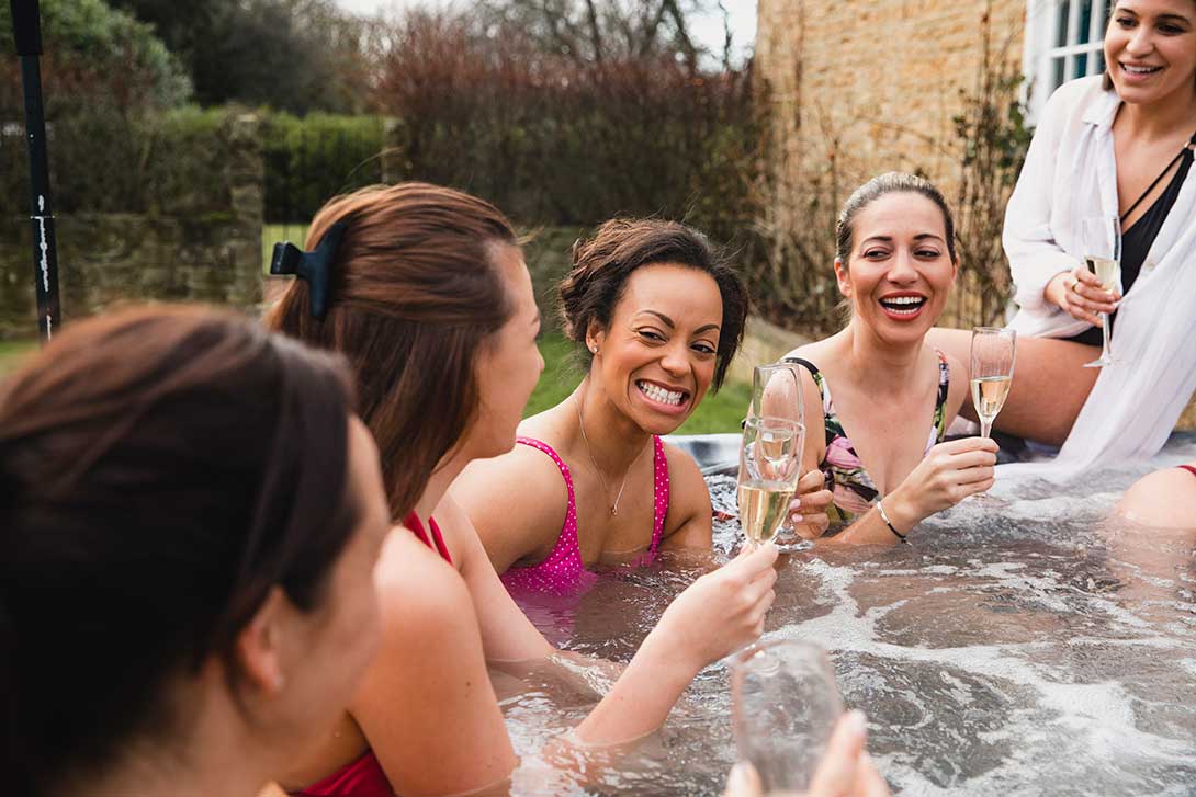women in jacuzzi drinking champagne